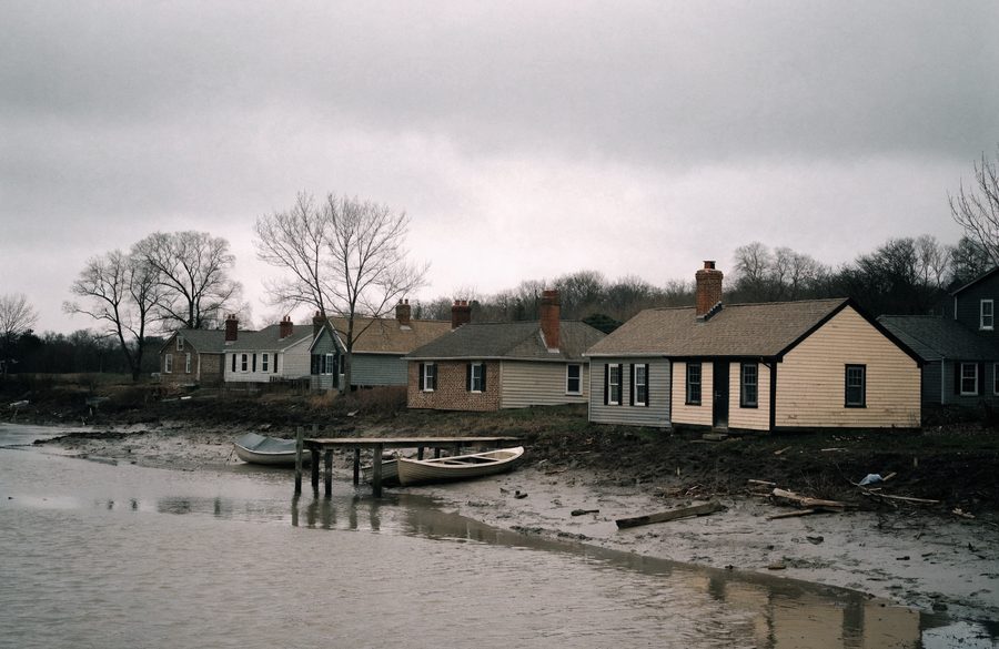 Waterfront bungalows with brick chimneys along the tidal shoreline in Essex